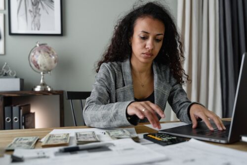 woman with documents, money, and calculator at desk